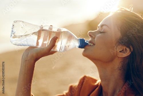 Foto Close up profile of a healthy woman drinking water from a bottle outdoors in war