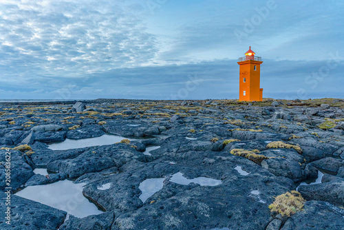 Orange lighthouse on volcanic coast, Iceland