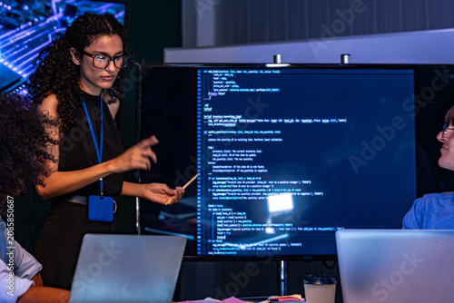 Foto Cinematic shot of a curly-haired developer and a bespectacled coder examine code