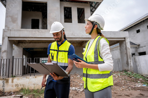 Civil construction site managers holding clipboard at residential construction site, inspection unfinished residential building during daytime, scene of house inspection and real estate development.