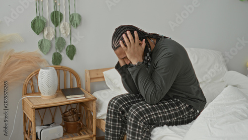 Foto Man sitting on bed covering face with hands, rubbing temples, visible bare hands and wristwatch in building bedroom; fatigue stress reflection