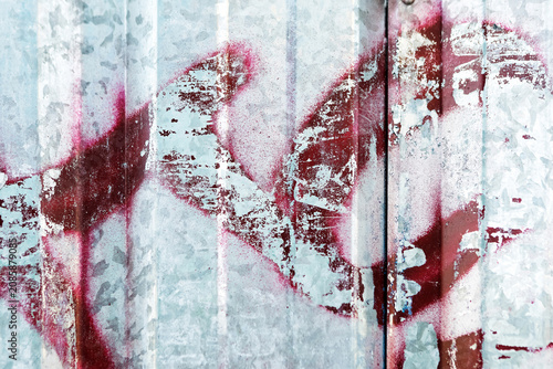 Rusted metal sheet with red graffiti, peeled paint, urban charm