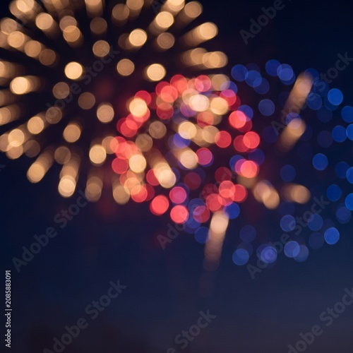 Blurred colorful fireworks exploding in the night sky creating a beautiful bokeh effect.