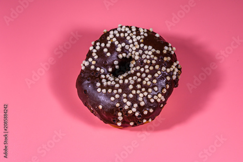 Donut with chocolate glaze on top isolated on a pink background