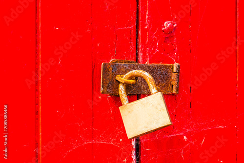 Bild auf Leinwand Weathered colourful bright red wooden beach hut door with a padlock on the beach