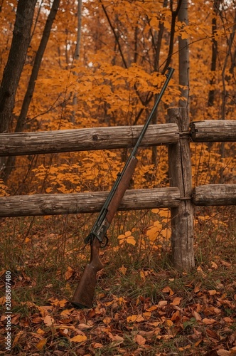 Rifle Resting Against Wooden Fence in Autumn Forest With Orange Leaves