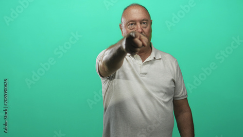 Quadro su tela Man pointing finger forward in studio against green screen wearing white polo and mustache; assertive command