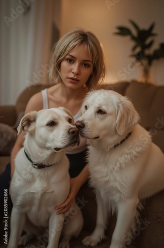 Woman Sits on Couch With Two Dogs at Home in Soft Light During Evening