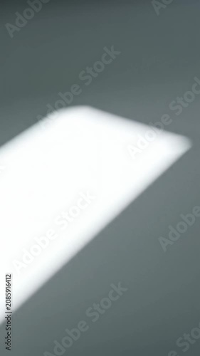 A pristine, expansive, minimalist white surface, bathed in high-key light, featuring a sharp diagonal ray and subtle grey shadow. Concept for modern elegance and precision