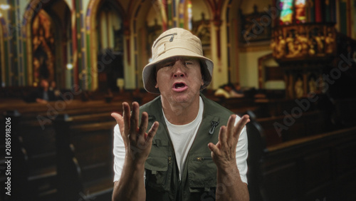 Tableau sur toile Man with open hands pleading gesture in church building wearing bucket hat and fishing vest, mouth open as if speaking; penitence solitude