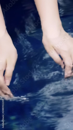 Extreme close-up macro video of soft, clean hands gently dipping into pristine, deep indigo water, creating subtle ripples under diffused light. Concept of purity and tranquility in Zen aesthetic