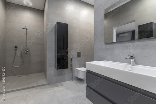 Quadro em tela A bathroom features a large shower with a water fixture, a sink with a faucet, and a toilet