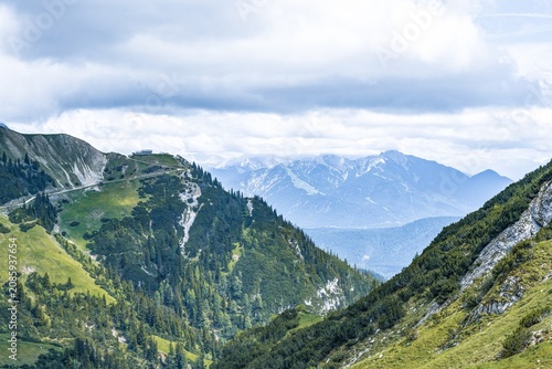 Scenic alpine landscape view of the Rotmoosalm in the Leutasch valley, Austrian Alps, mountain hut on a green ridge with dramatic clouds, summer hiking destination.