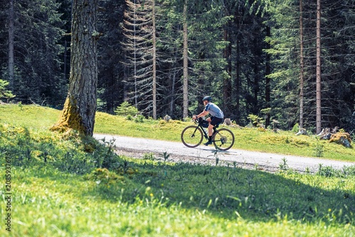 Gravel cyclist riding on a scenic forest road in the Alps