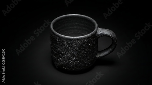 Minimalist black textured ceramic mug on a dark background, rustic handmade pottery cup