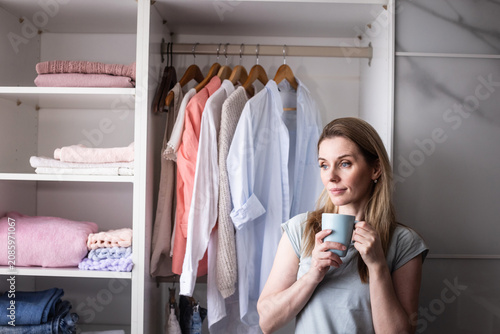 Tableau sur toile Woman arranging folded clothes on shelf, careful attention