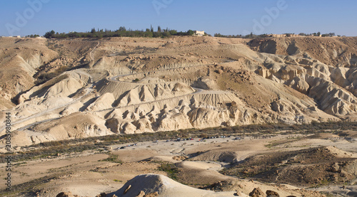 Fotografie A landscape with a serpentine road descending from the settlement Midreshet Ben-Gurion in the Negev Desert to a wide dry wadi Zin