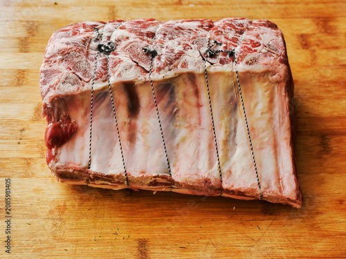 Huge carvery rib roast on the bone is on a wooden cutting board. Butcher craft and skill product. Top quality beef meat with high value and price tag due to premium cut and complicated production.