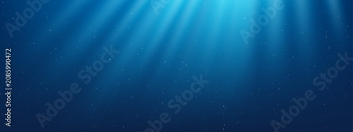 Fotografie Underwater blue ocean background with light rays shining through water surface