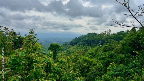 Lush Green Hilly Landscape Under Overcast Sky.