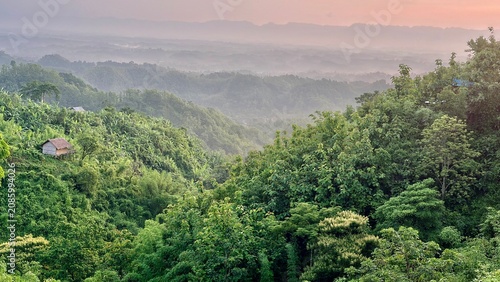 morning in the mountains. Lush Green Hills with Small House in Misty Landscape at Sunrise.