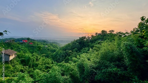 Lush Green Hills with Small House in Misty Landscape at Sunrise.