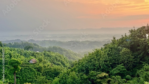 Rolling Hills and Forest Landscape with Small Hut at Dawn