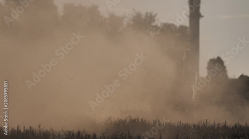 Close-up Cinematic Shot of Combine Harvester Harvesting Grain with Rising Dust at Sunset