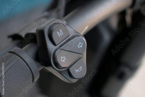 Title: Close up of electric scooter handlebar control switches for mode turn signals and horn in