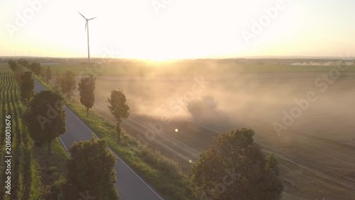 Aerial Follow Shot: Combine Harvester Entering and Beginning Harvest in Golden Field at Sunset