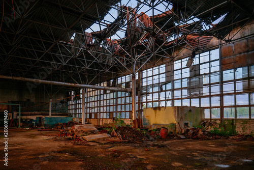 Old ruined factory building with broken roof and rusty remains of machines