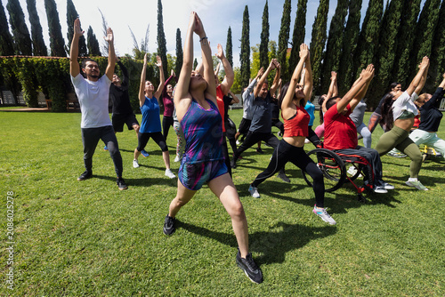 Large Group of Latin sporty multi age people stretching in training class with mexican people in wheelchair outdoors in Mexico Latin America. Diverse hispanic group in inclusion concept