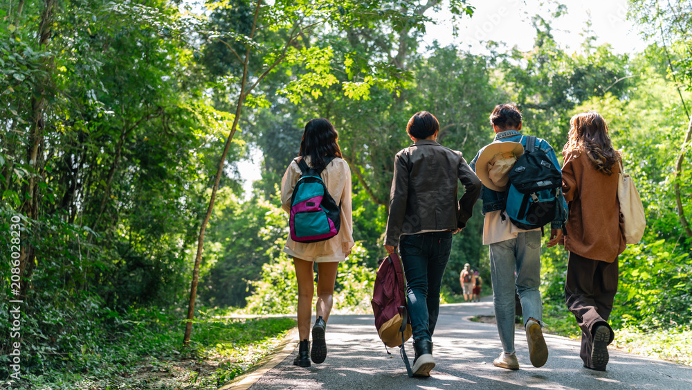 Fototapeta premium Group of Generation z people friends hiking through forest trail exploring nature together during eco travel adventure enjoying outdoor recreation sustainable tourism and healthy active lifestyle