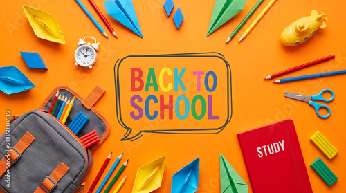Back to school multi-colored text on bright tangerine orange background with kids backpack notebooks submarines colorful clay blocks