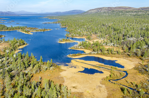 Aerial view of Rogen nature reserve featuring a vast blue lake, numerous small islands, dense coniferous forests, and golden marshlands in Tannas, Jamtland County, Sweden.