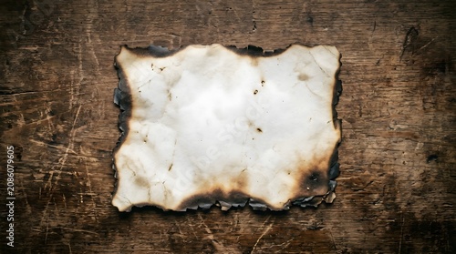 Burnt paper on wooden surface background.