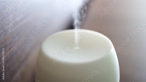 Static Shot Of White Ultrasonic Humidifier Releasing Steady Mist Into Calm Indoor Room Beside Wooden Surface With Soft Natural Light.