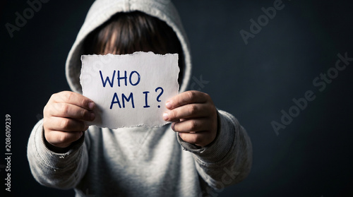 Anonymous person in hoodie holding a Who Am I question sign