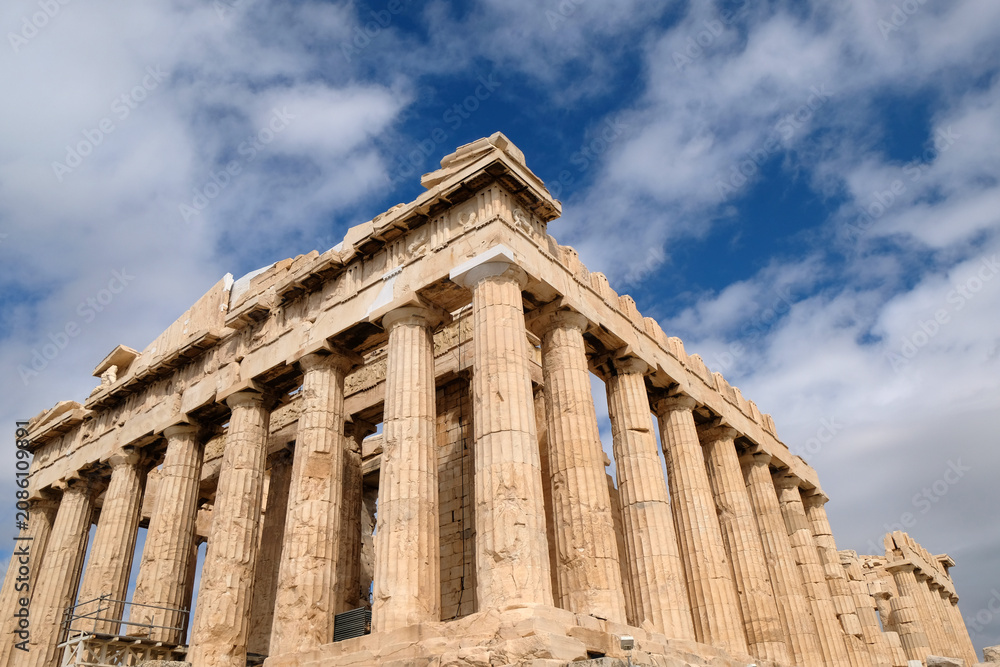 Fototapeta premium ancient Parthenon stands tall under a blue sky in Athens, Greece during midday with clouds in the background.