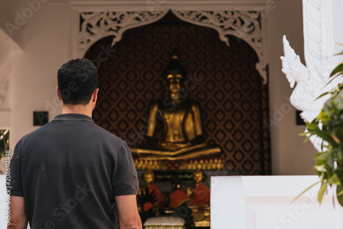 Εκτύπωση καμβά Man from behind observing a golden Buddha statue, experiencing spirituality and