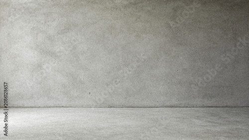 A minimalistic grey concrete wall and floor, showcasing a modern industrial interior design. The space is empty and well-lit, ideal for various backgrounds.