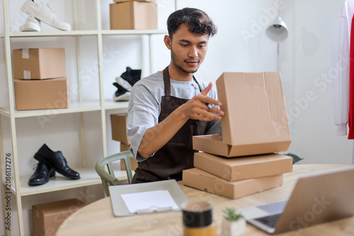 Asian Male Merchant Opening Cardboard at His Work Desk