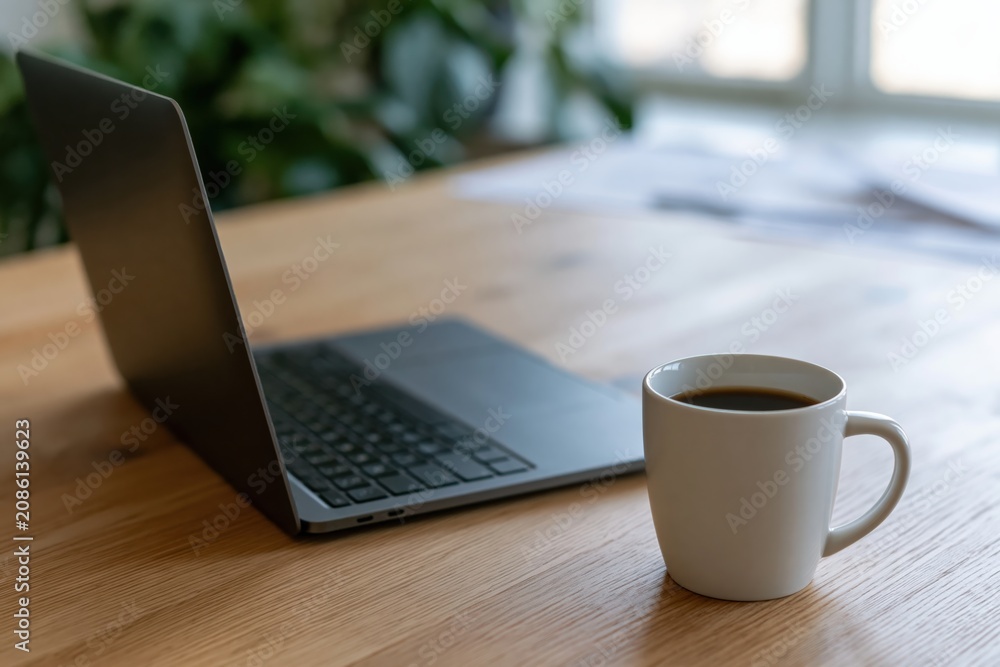 Fototapeta premium Laptop and computer on a wooden desk with a steaming coffee mug in a workspace