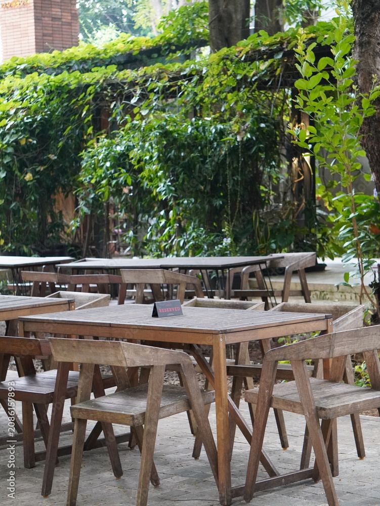 Obraz premium A small rectangular black reserved sign sits centered on a weathered wooden table with matching chairs in an outdoor setting