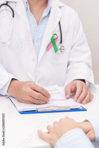 Doctor and patient having a medical consultation for green and pink ribbon to patient for concept of October Metastatic Breast Cancer Awareness month, National Cancer Survivors Month and Pink October