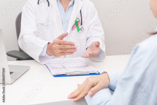 Doctor and patient having a medical consultation for green and pink ribbon to patient for concept of October Metastatic Breast Cancer Awareness month, National Cancer Survivors Month and Pink October