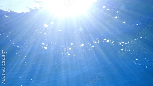 Ocean blue underwater with sunrays, Underwater Sea Deep Water Abstract Sunshine, sea wave , clean waters in summer time, Natural underwater seascape, sand on ocean floor and water surface sunlight.