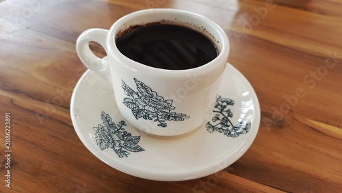 Cup of Black Coffee on Saucer with Floral Pattern on Wooden Table. Business Background