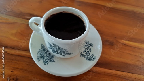 Cup of Black Coffee on Saucer with Floral Pattern on Wooden Table. Business Background