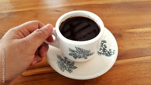 Cup of Black Coffee on Saucer with Floral Pattern on Wooden Table. Business Background